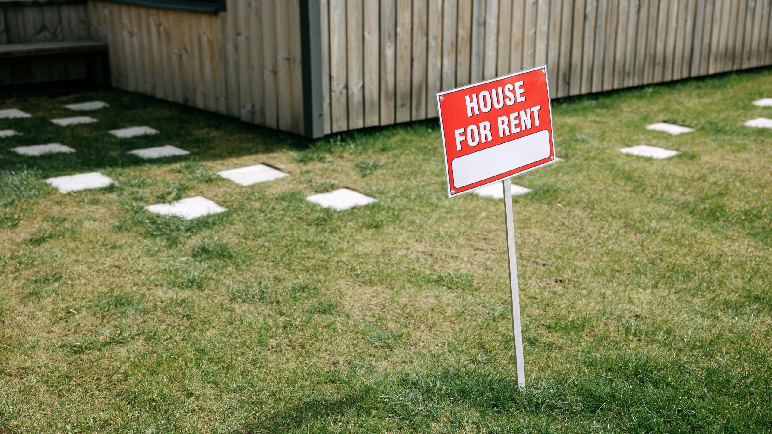 a sign in a yard advertising a house for rent.