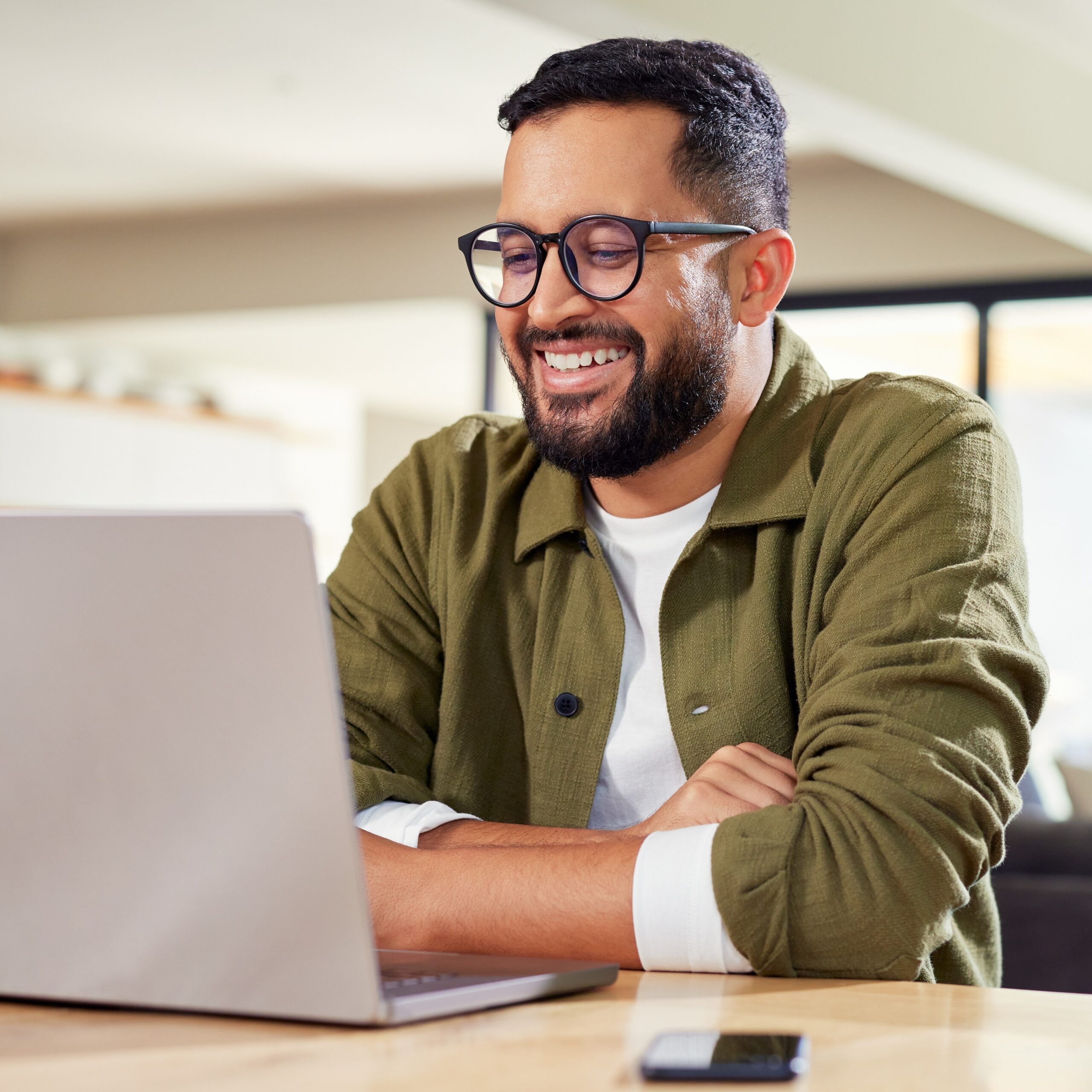 A man sitting at a desk using a computer. He is using the EstateGather Rental Property Calculator. And he is happy to do so.