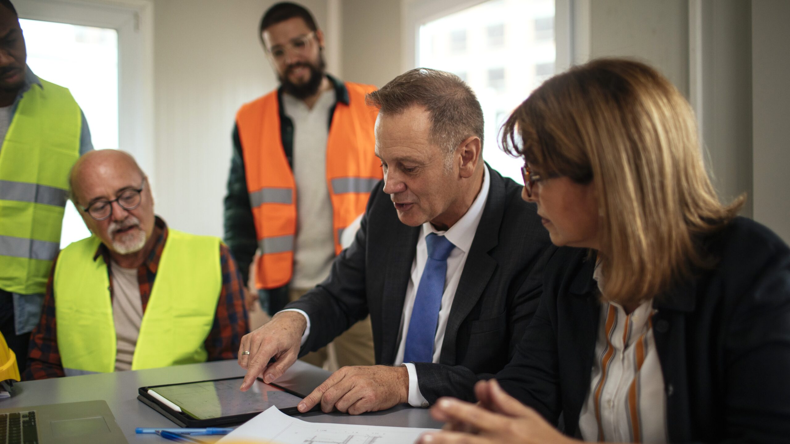 A team of property professionals and contractors reviews expense reports and site plans, evaluating a building's financial performance and operating costs.
