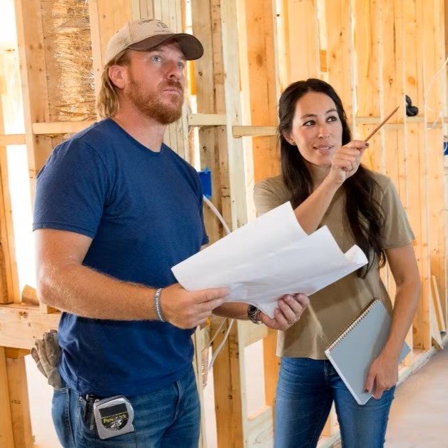 A man and woman review renovation plans inside a property under construction, discussing upgrades that will enhance value and appeal—symbolizing strategic improvements that drive return on investment in real estate.