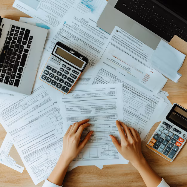 A calculator and tax documents on a desk with a small house model nearby. Goal: Reinforce that real estate investing offers practical, legal ways to reduce taxable income.